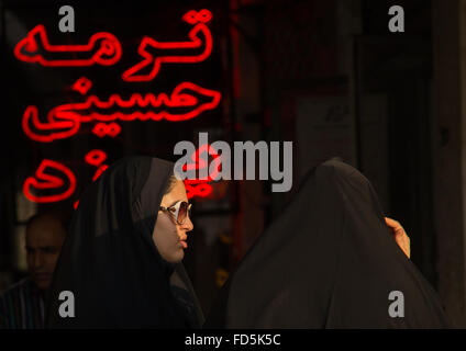 Les femmes voilées en face de néons rouge, Central District, Téhéran, Iran Banque D'Images