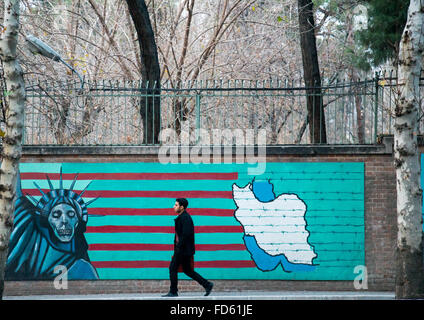 L'homme en passant en face de propagande murale anti-américaine dépeignent slogan statue liberty skeleton sur le mur de l'ancienne ambassade des États-Unis, Central District, Téhéran, Iran Banque D'Images