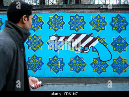 L'homme en passant en face de propagande murale anti-américaine sur le mur de l'ancienne ambassade des États-Unis, Central District, Téhéran, Iran Banque D'Images