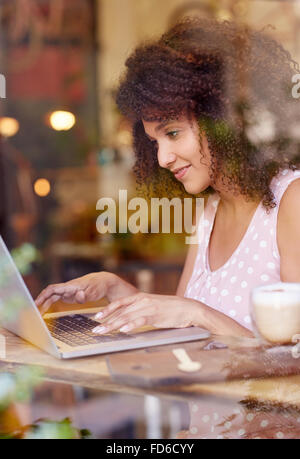 Jeune femme travaillant sur son ordinateur portable dans un café Banque D'Images