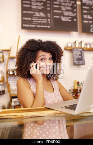 Femme à la recherche jusqu'à vous par derrière son comptoir de cafe Banque D'Images