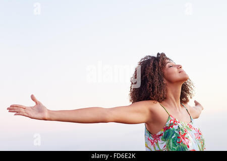 Femme avec les bras tendus et les yeux fermés en plein air Banque D'Images