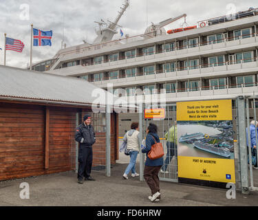 Akureyri, Islande du Nord, l'Islande. 1er août 2015. Les passagers de la Compagnie du Ponant navire de croisière de luxe Le Boreal passer au travers d'une clôture de protection surveillée par un garde de sécurité dans le nord-est de port d'Akureyri, Islande, le deuxième plus grande zone urbaine dans le fjord Eyjafjordur. C'est un important centre de pêche où le tourisme est devenu un secteur croissant de l'économie. © Arnold Drapkin/ZUMA/Alamy Fil Live News Banque D'Images