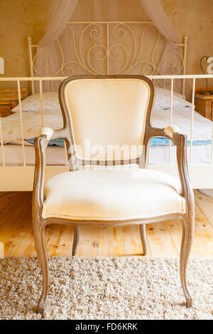 De l'intérieur d'une belle chambre dans vintage style rural. Chambre avec lit double à baldaquin confortable et rétro chaise. Design. Banque D'Images