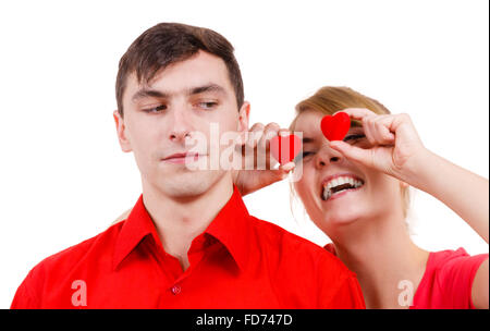 Couple. Petit ami sérieux et sa petite amie follement amusante holding coeurs rouges au-dessus des yeux. Valentines Day ou amour non partagé. Banque D'Images