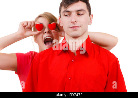 Couple. Petit ami sérieux et sa petite amie follement amusante holding coeurs rouges au-dessus des yeux. Valentines Day ou amour non partagé. Banque D'Images