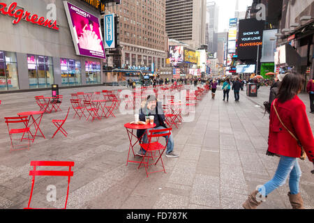 D'un homme décent espagnol parler au téléphone cellulaire en assis sur chaise rouge à Times Square, New York City Banque D'Images