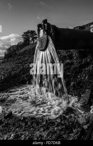 L'eau s'écoule des déchets d'une sortie du tuyau d'eau de déchets dans la rivière dans le Devon UK Banque D'Images