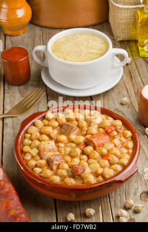 Cocido espagnol, la soupe dans un bol blanc, l'huile d'olive, adjuvants et pots sur une table en bois Banque D'Images