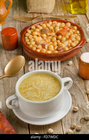 Cocido espagnol, la soupe dans un bol blanc, l'huile d'olive, adjuvants et cuillère d'or sur une table en bois Banque D'Images