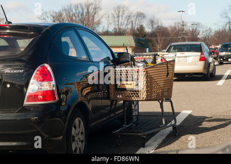 Chariot d'épicerie s'appuyant sur voiture en stationnement - USA Banque D'Images