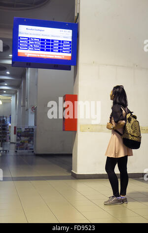 Femme regardant l'information board sur la plate-forme à la gare Banque D'Images