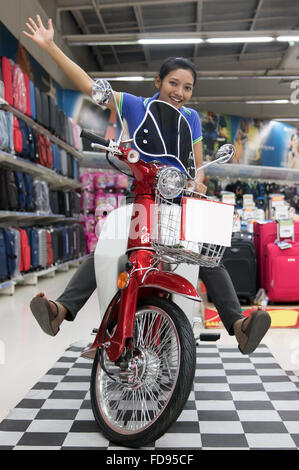 Cheerful girl est assis sur une moto dans la boutique Banque D'Images