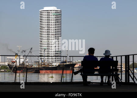 Couple assis sur un banc au bord de l'eau Banque D'Images
