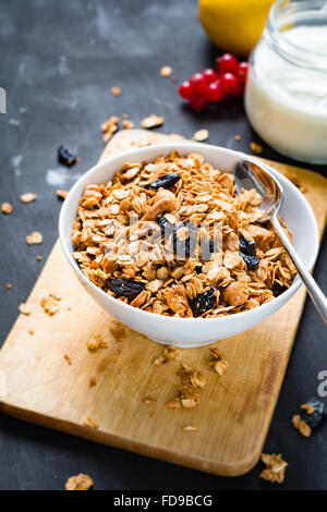 Granola maison aux noix et fruits secs en blanc bol, pot de yaourt frais et de fruits sur fond de bois Banque D'Images