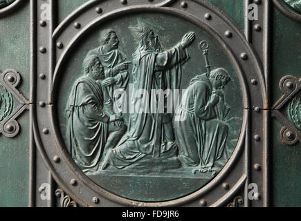 Saint Adalbert priant avec son frère Saint Gaudence Radim. Relief en bronze conçue par l'artiste tchèque Josef Mánes sur la porte principale de l'église des Saints Cyrille et Méthode sur Karlinske square dans le quartier de Karlin à Prague, République tchèque. Banque D'Images