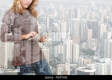 Double Exposure of woman using tablet de la technologie et de l'arrière-plan des constructions urbaines Banque D'Images