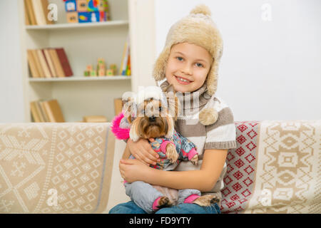 Petite fille et son animal vêtu de vêtements chauds. Banque D'Images