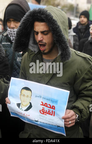 Hébron, en Cisjordanie, en territoire palestinien. 29 janvier, 2016. Un palestinien est titulaire d'une affiche portant le portrait d'un journaliste palestinien Mohammed al-Qiq qui est incarcéré dans une prison israélienne au cours d'une manifestation à l'appui de sa grève de la faim dans la ville de Cisjordanie d'Hébron, le 29 janvier 2016. Qiq est placé sous détention administrative controversée d'Israël droit, qui permet à l'état de maintenir des suspects pour des périodes de six mois renouvelables sans procès et il refuse de la nourriture depuis le 25 novembre pour protester contre la ''la torture et mauvais traitements qu'il a été soumis à des interrogatoires Banque D'Images