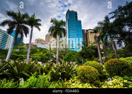 Jardins et des gratte-ciel vu à Ayala Triangle Park, à Makati, Metro Manila. Banque D'Images