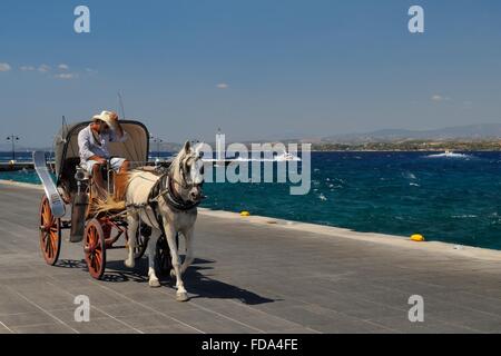 Cheval et sa voiture sur le front de mer de la ville de Spetses, Spetses, îles saroniques, Attique, Péloponnèse, Grèce. Banque D'Images