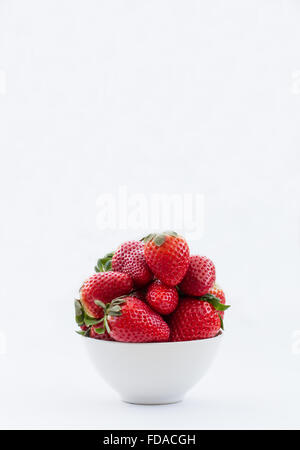 Un bol plein de fraises fraîches isolées sur un fond blanc. L'orientation portrait. Banque D'Images