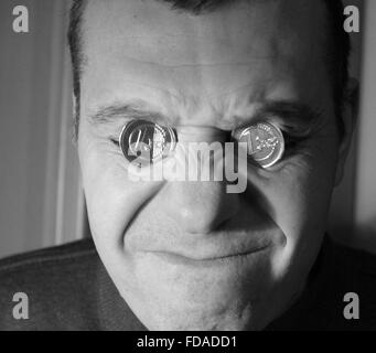 Jeune homme avec deux pièces de briller sur les bases d'Yeux avec grimace de douleur sur le visage perdant en temps de crise Banque D'Images