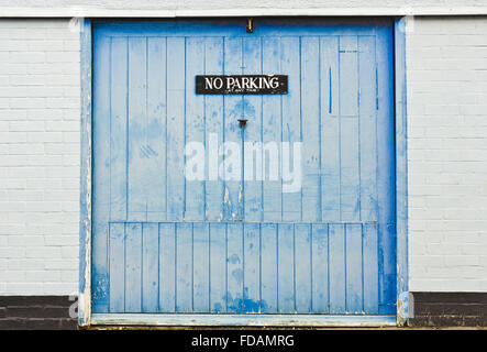 Un avis d'avertissement aucun stationnement sur une porte de garage en bois bleu Banque D'Images