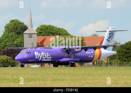 Flybe ATR 72 EI-REL taxiing a passé St. Lawrence et All Saints église qui est sur le bord du périmètre de l'aéroport de Londres Southend Banque D'Images