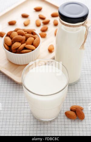 Le lait d'amande en verre et la bouteille sur la table avec amandes Banque D'Images