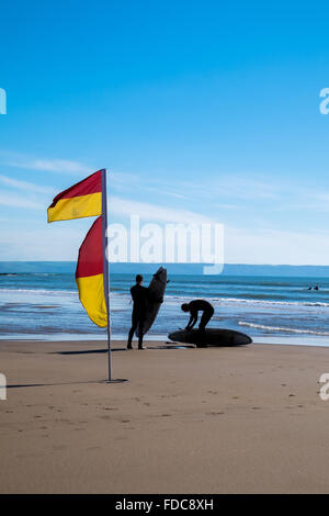 Les surfeurs à côté d'un indicateur d'avertissement de natation à Croyde beach, North Devon, England, UK Banque D'Images