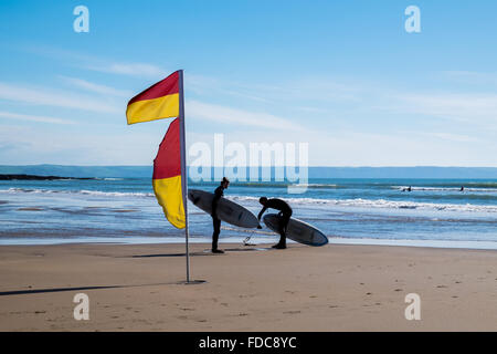 Les surfeurs à côté d'un indicateur d'avertissement de natation à Croyde beach, North Devon, England, UK Banque D'Images