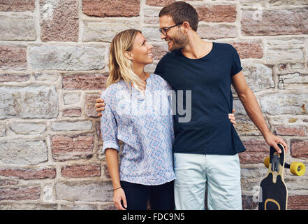 Trois quart d'un doux sourire amoureux les uns les autres contre mur en béton. Banque D'Images