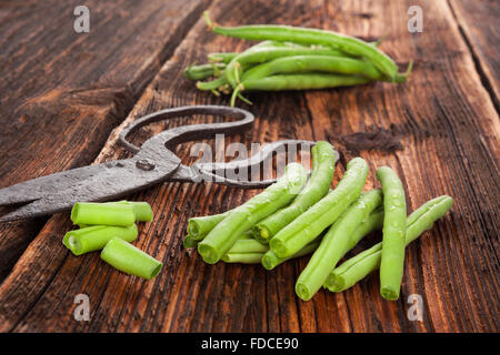 Les haricots verts frais avec des gouttes d'eau sur la table en bois brun texture fine. Manger des légumes frais. Banque D'Images