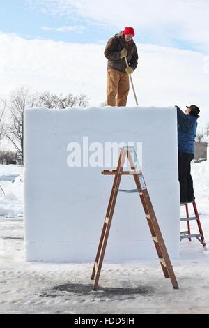 Deux hommes se préparent à se tailler un bloc de neige géant à la compétition de sculpture sur neige du Carnaval d'hiver au Minnesota. Banque D'Images