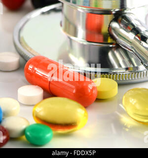 Stéthoscope et des médicaments oraux colorés sur fond blanc. Banque D'Images