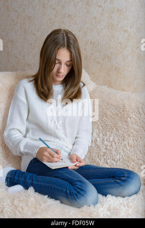 La jeune fille attire l'assis sur un canapé avec une couverture de fourrure Banque D'Images