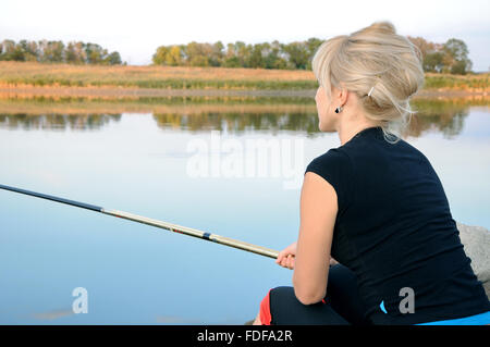 Femme pêcher dans la rivière sur une vieille jetée en bois Banque D'Images