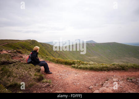 Une femelle walker looking out sur les sommets de Pen Y Fan et fan de Cribyn Y Big dans les Brecon Beacons, le Pays de Galles Banque D'Images