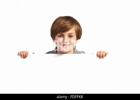 Little Boy holding a blank billboard blanc Banque D'Images