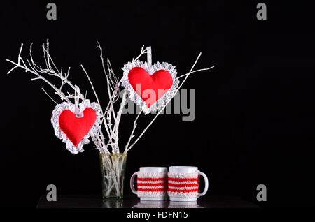 Paire de coeurs rouges sur une branche avec deux mugs Banque D'Images