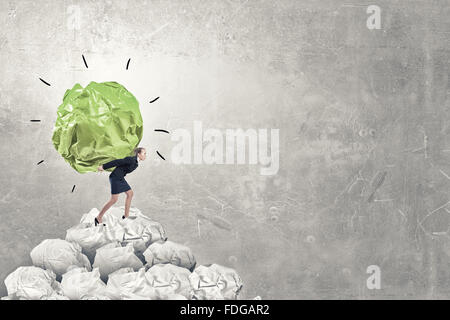 Femme transportant avec grand effort boule de papier froissé comme signe de la créativité Banque D'Images