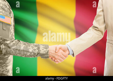 Soldat américain en uniforme et civils man shaking hands with drapeau national sur l'arrière-plan - Mali Banque D'Images