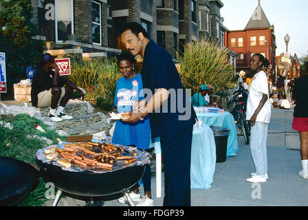 Washington, DC., USA, 1994 Révérend Jesse Jackson se tient sur son grill au charbon de la cuisson des hot-dogs lors d'une fête de quartier en face de sa maison, à Washington DC. Jesse Louis Jackson, Sr. est un militant des droits civiques aux États-Unis et pasteur baptiste. Il était candidat à l'investiture démocrate à la présidence en 1984 et 1988 et a servi comme une ombre Sénateur des États-Unis pour le District de Columbia de 1991 à 1997. Il est le fondateur des organisations qui ont fusionné pour former Rainbow/PUSH. Ancien représentant américain Jesse Jackson, Jr. est son fils aîné. Credit : Mark Reinstei Banque D'Images