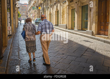 Couple, vue arrière d'un couple de personnes âgées à faire leur chemin jusqu'à la Piazza Umberto à Enna, Sicile, pour commencer la soirée. Banque D'Images