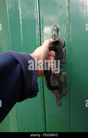 Tirant sur la porte, la main d'un homme sur une vieille porte loquet. Banque D'Images