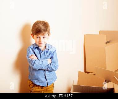 Peu cute boy dans la salle vide, remoove de nouvelle maison. La maison seule boîtes emong Banque D'Images