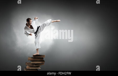 Jeune homme karaté déterminé on pile of books Banque D'Images