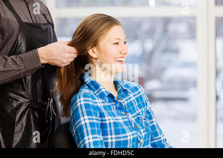 Jeune femme en fauteuil à barbiers et homme coiffure Banque D'Images