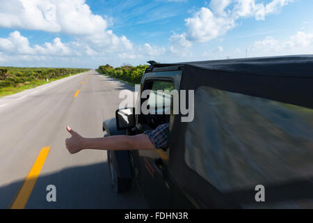 Pouce vers le haut de la fenêtre de Jeep sur la route en bord de vide, Cozumel, Mexique Banque D'Images